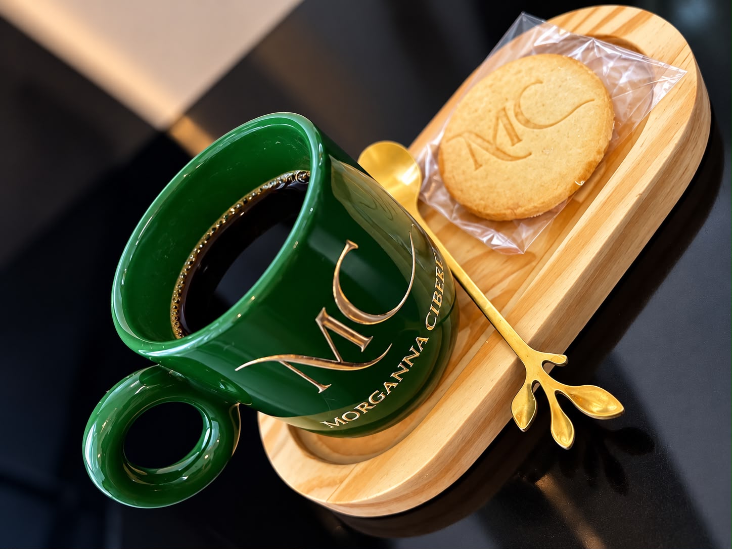 Café servido em xícara verde com o monograma da Morganna Ciberiê, no salão